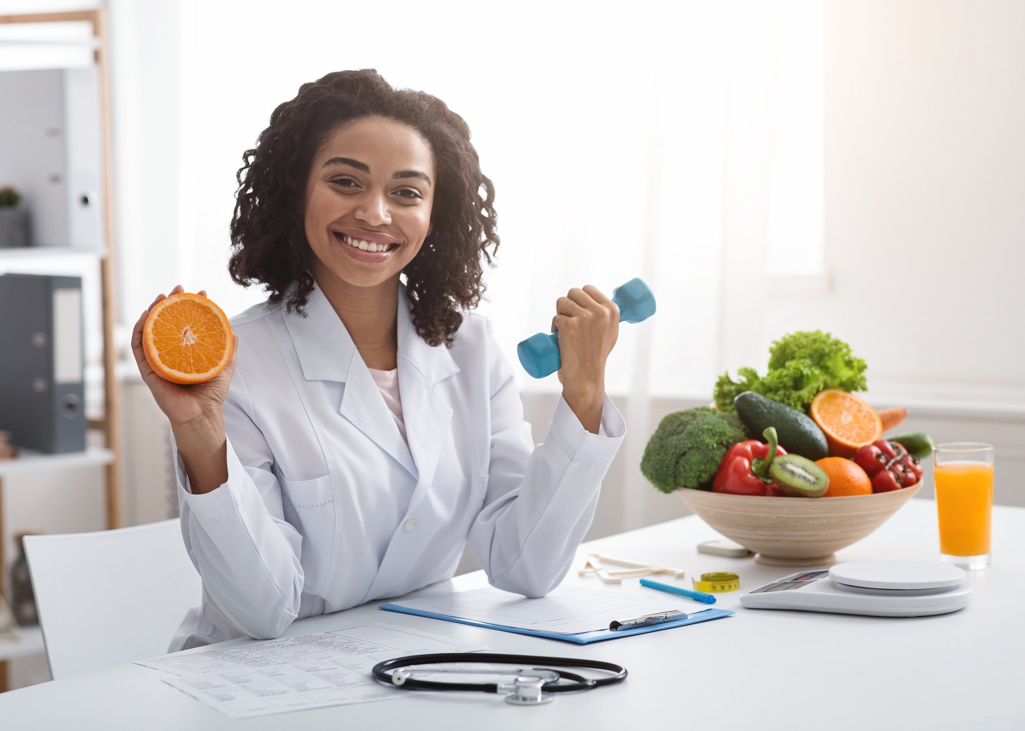 happy-woman-doctor-holding-orange-and-barbell-in-c-2026-01-08-23-26-20-utc