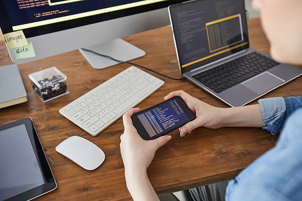 desarrolladora-sostiene-un-celular-en-su-lugar-de-trabajo