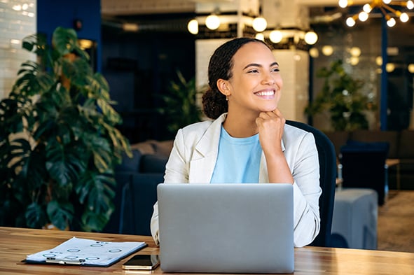 mujer feliz en un restaurante trabajando enfrente de su computadora mientras sonrie