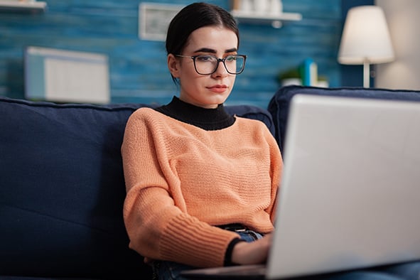 mujer en casa con su computadora concentrada escribiendo 