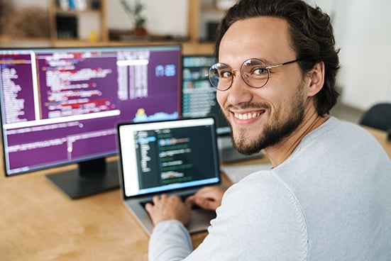 programador en su oficina trabajando con varias computadoras