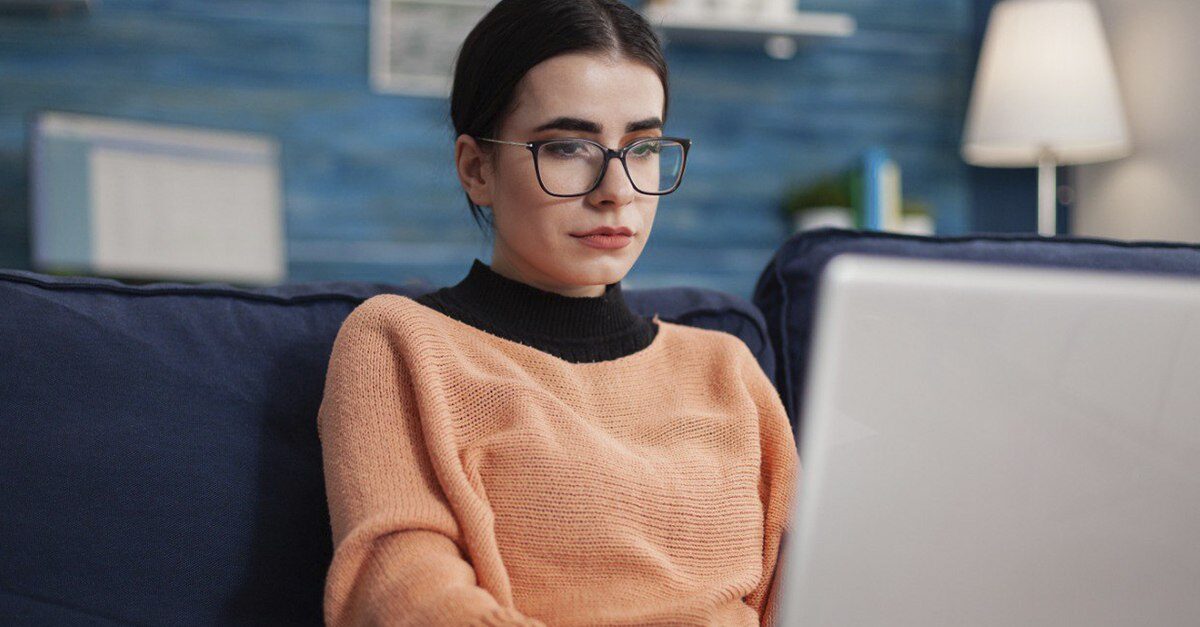 programadora-con-lentes-sosteniendo-laptop-en-un-sofa