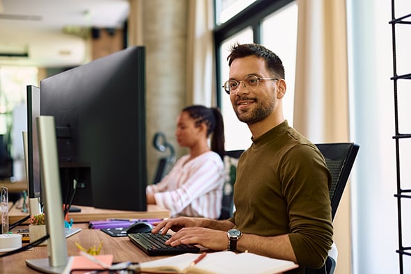 programador feliz trabajando en su computadora en una oficina