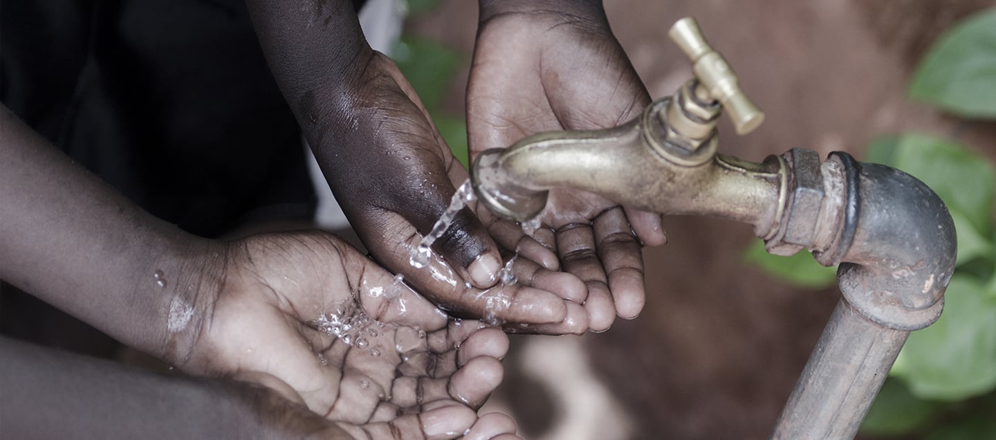 Manos de niños africanos toman agua de la llave